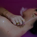 model in pink water wearing brass jewelry