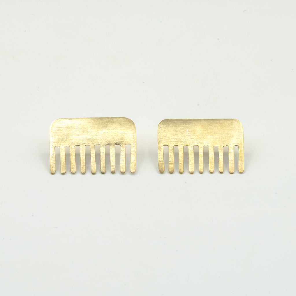 brass comb shaped earrings on white background