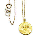 Stamped brass circle pendant with sterling silver chain on white background