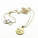 Stamped brass circle pendant with sterling silver chain on white background