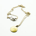 Brass circle pendant with sterling silver chain on white background