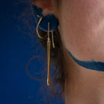 Model using long brass earrings and arch hoops