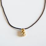 Sculpted brass pendant on this purple silk rope