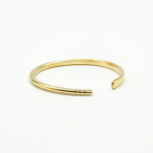 hand forged brass bangle with three cut notches on white background