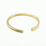 hand forged brass bangle with three cut notches on white background