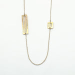 silver chain with brass cutout pieces necklace on white background