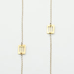 silver chain with brass cutout pieces necklace on white background