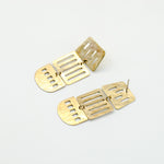 long brass cutout earrings on white background