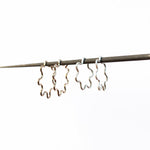 Argolas prateados ondulados em forma de flor sobre fundo branco