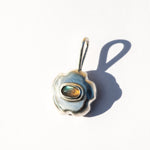 Pendente de prata em forma de flor com uma pedra preciosa de labradorita sobre um fundo branco