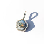Pendente de prata em forma de flor com uma pedra preciosa de labradorita sobre um fundo branco