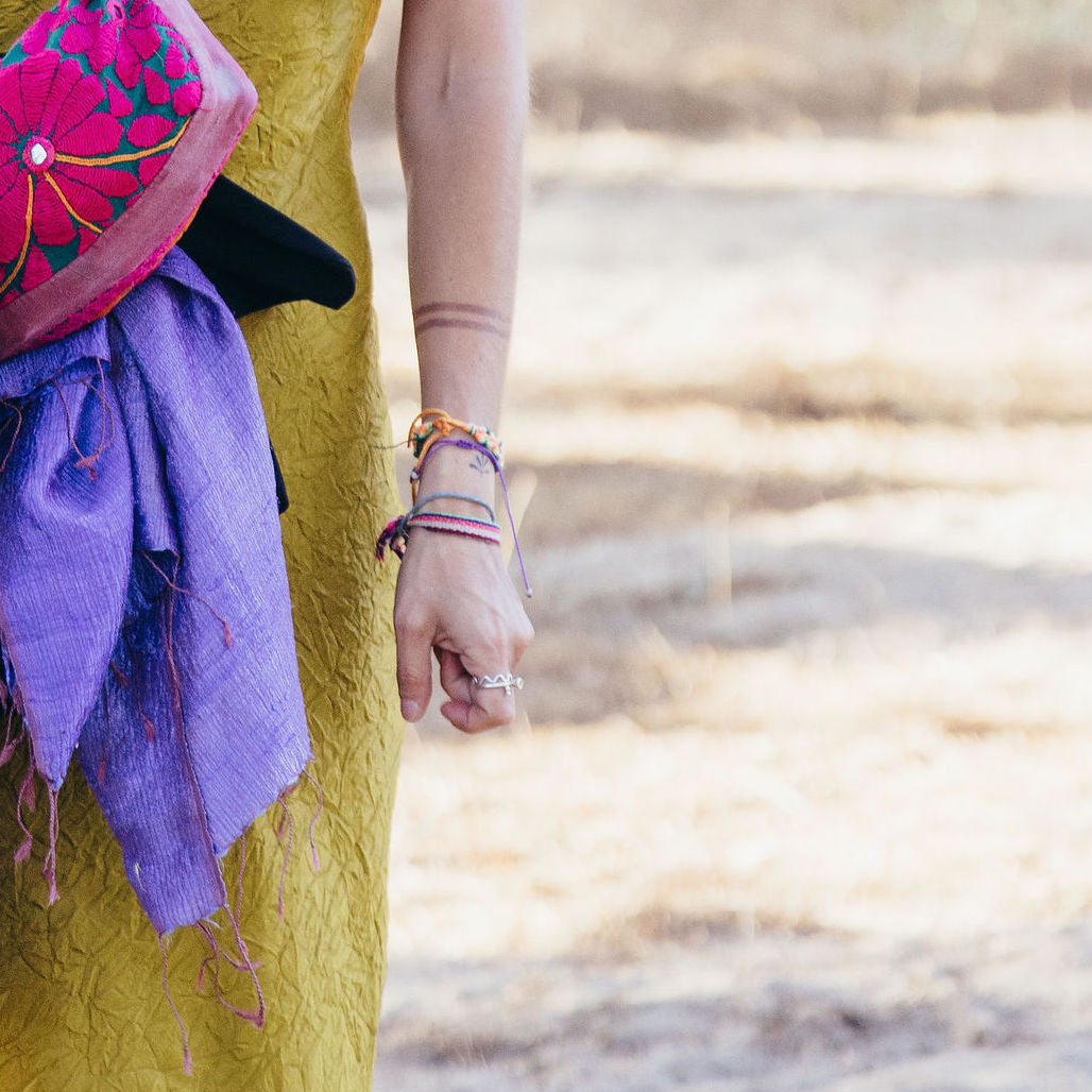 Person wearing a colorful headscarf, purple shawl and silver rings