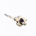 Silver flower-shaped pendant with an amethyst gemstone on a white background