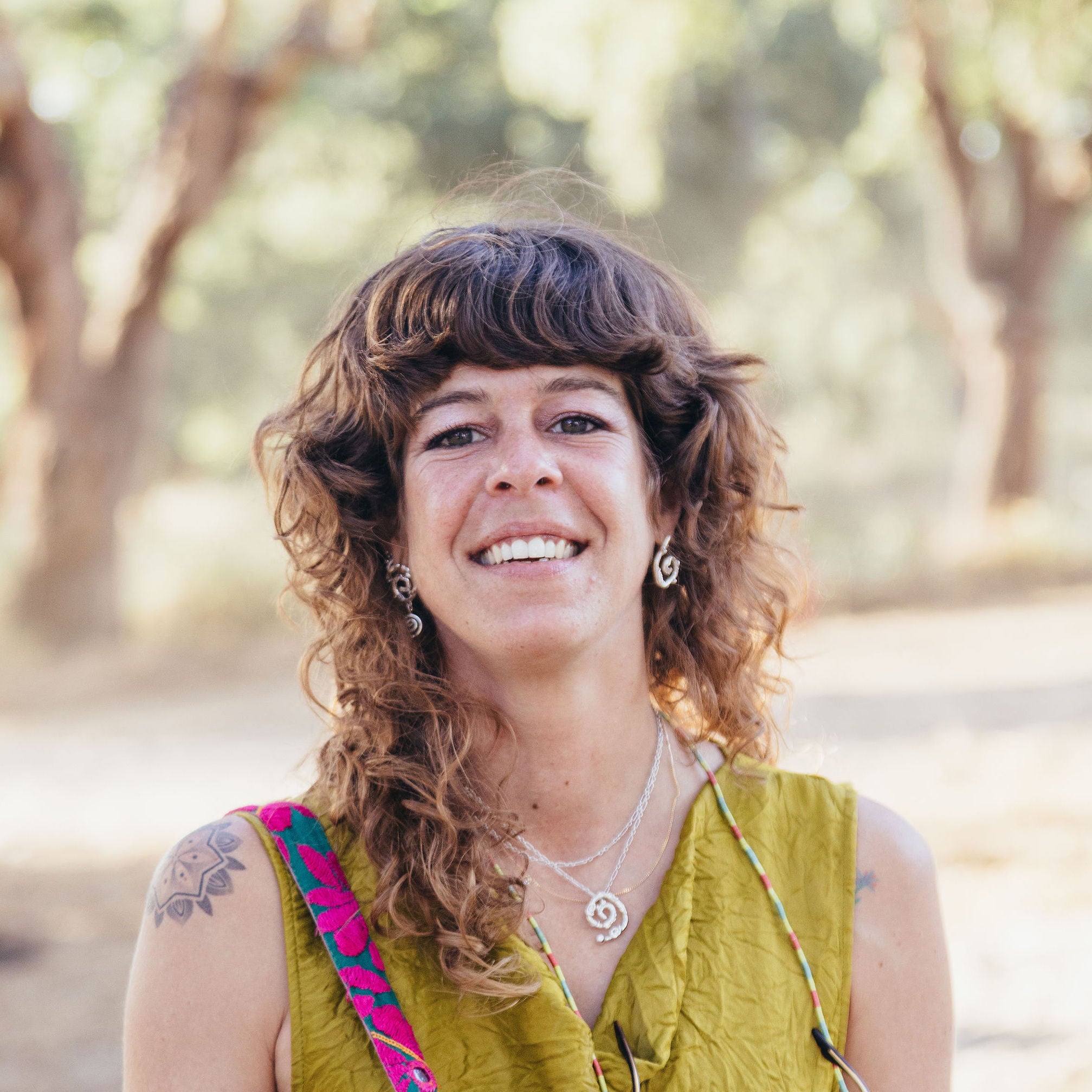 Woman with shoulder-length curly hair wearing silver jewelry