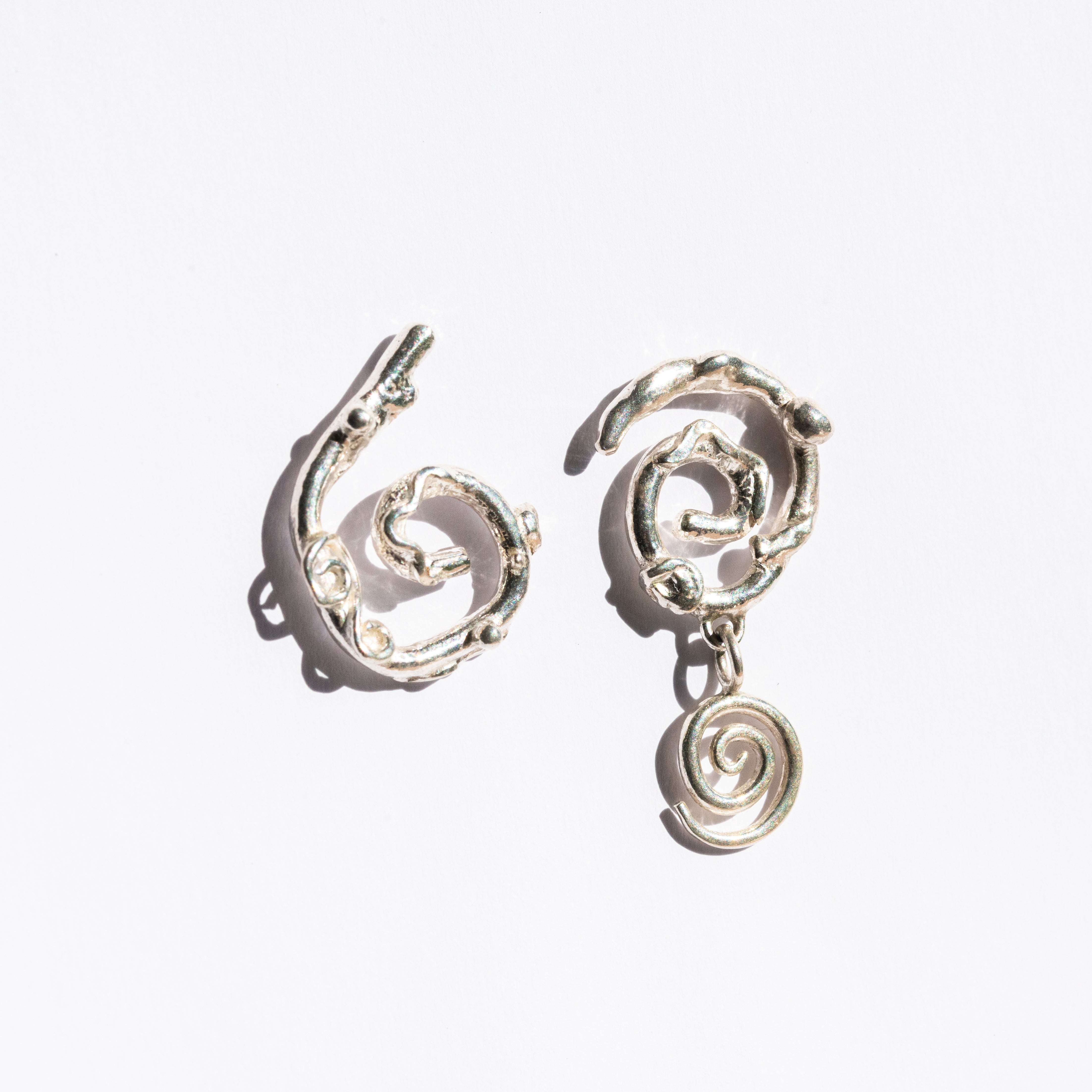Silver asymmetrical spiral earrings on a white background