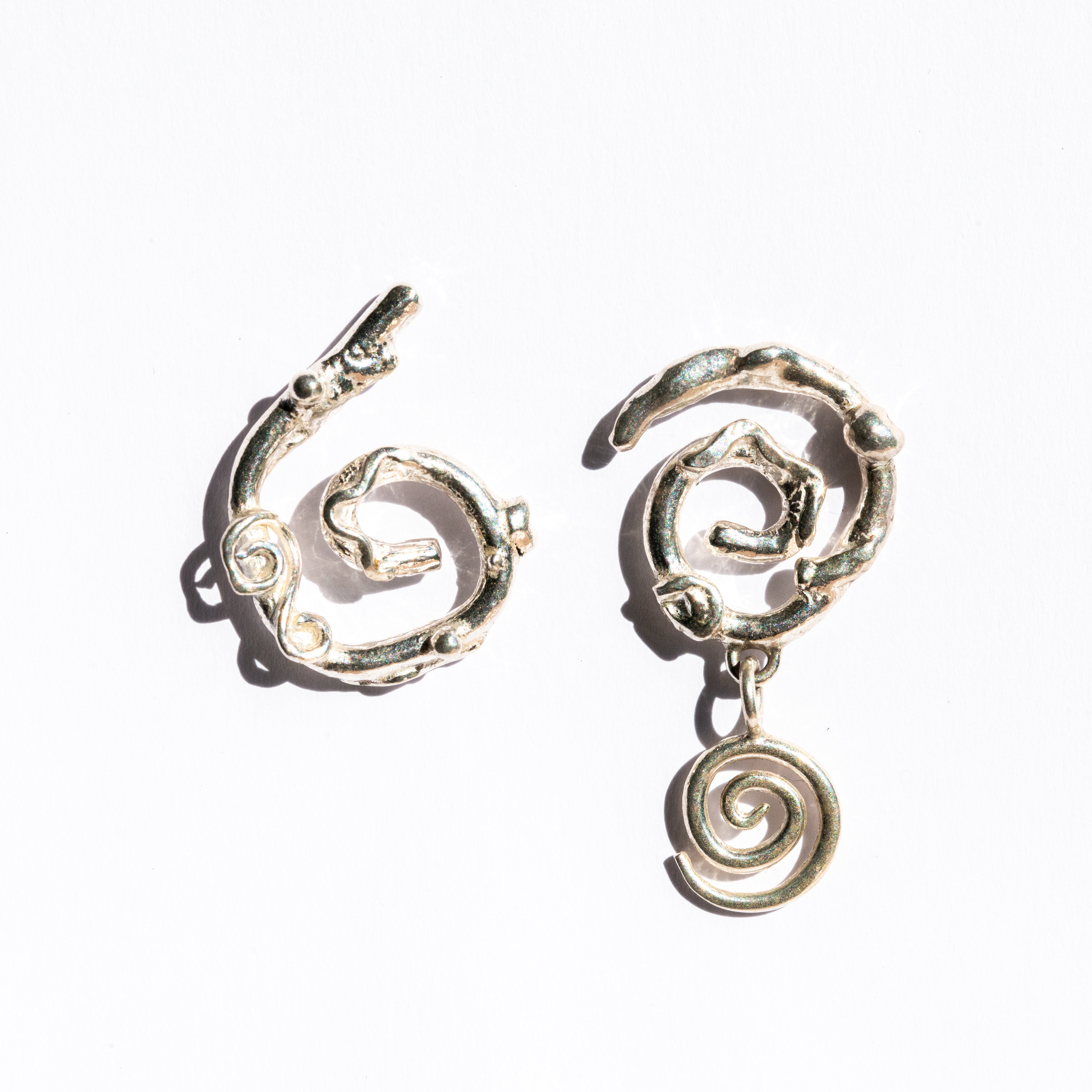 Silver asymmetrical spiral earrings on a white background