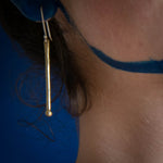 model using long brass balled earrings