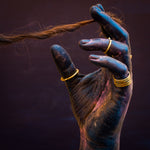 painted hand holding hair with brass rings
