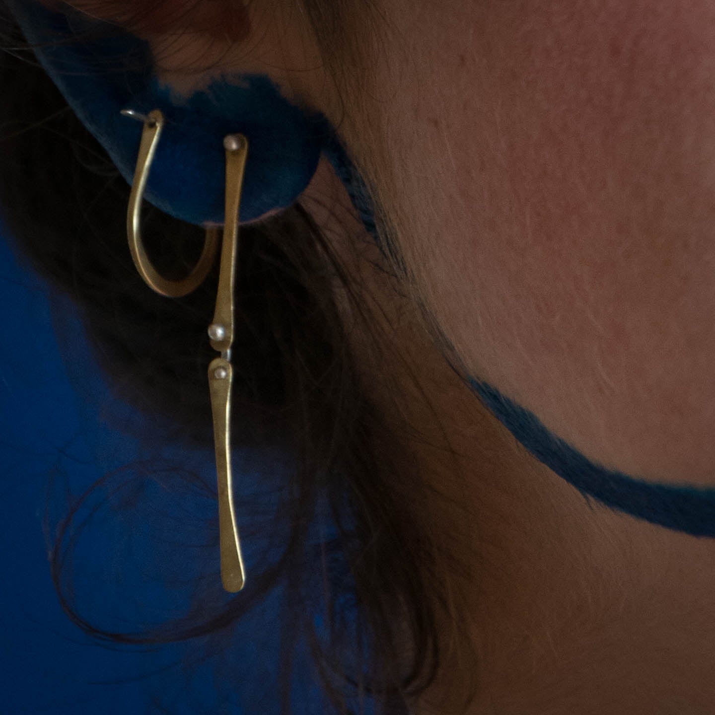 Model using brass arch hoops and long brass earrings