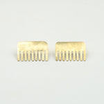 brass comb shaped earrings on white background