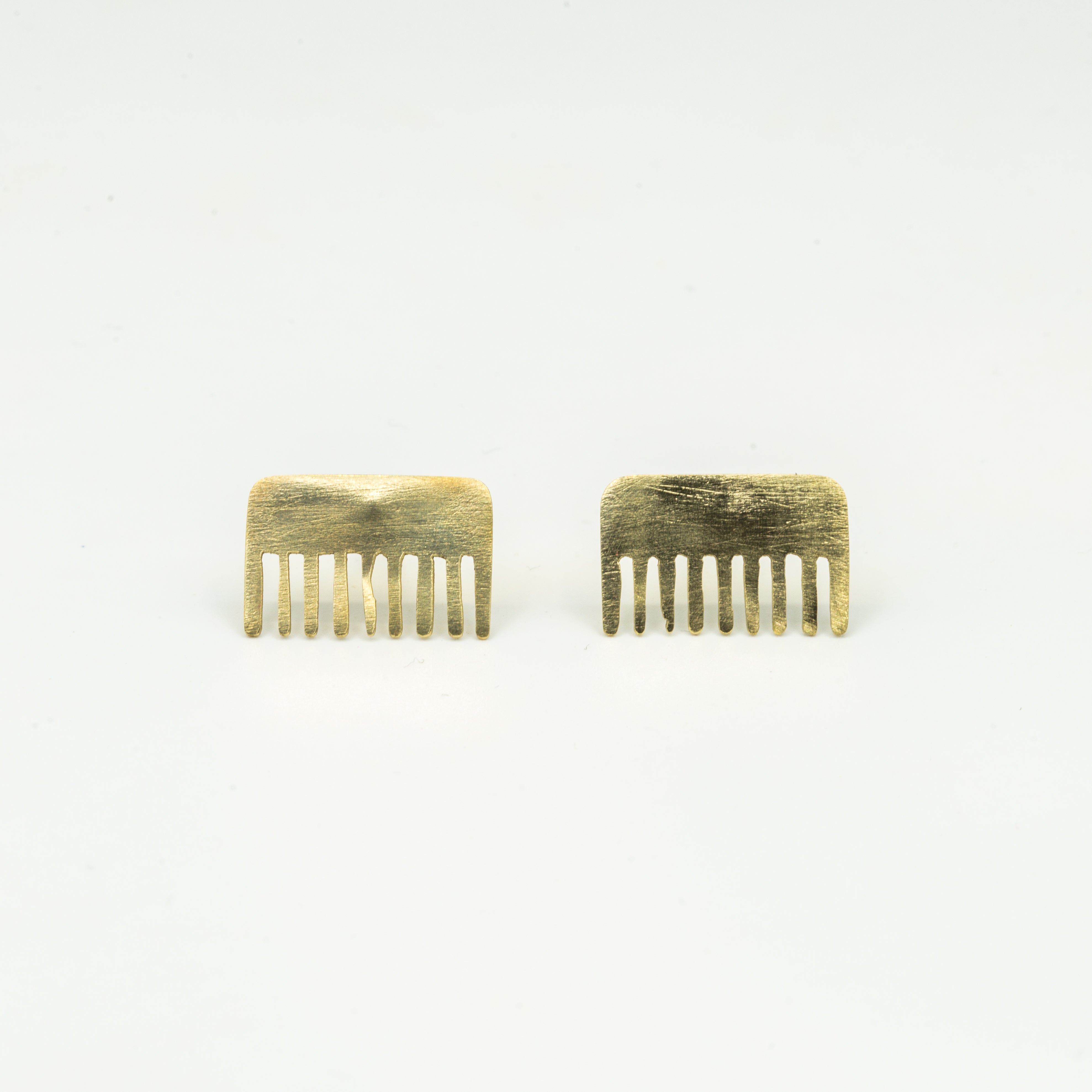 brass comb shaped mini stud earrings on white background