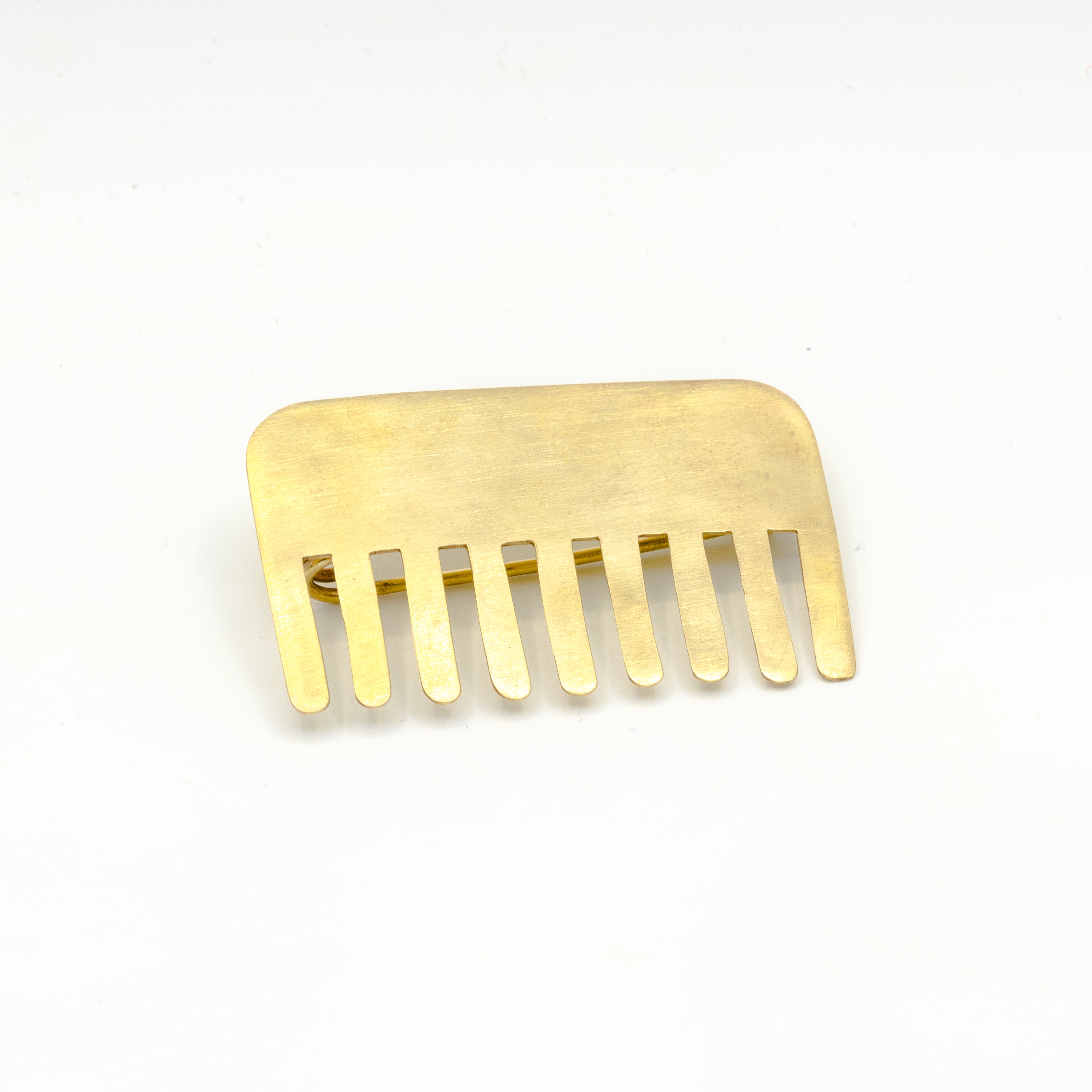 brass comb shaped pin on white background