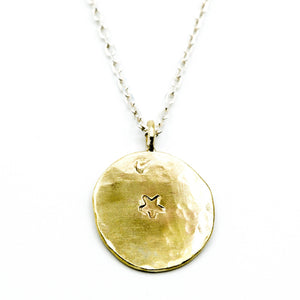 Star stamped brass circle pendant with sterling silver chain on white background
