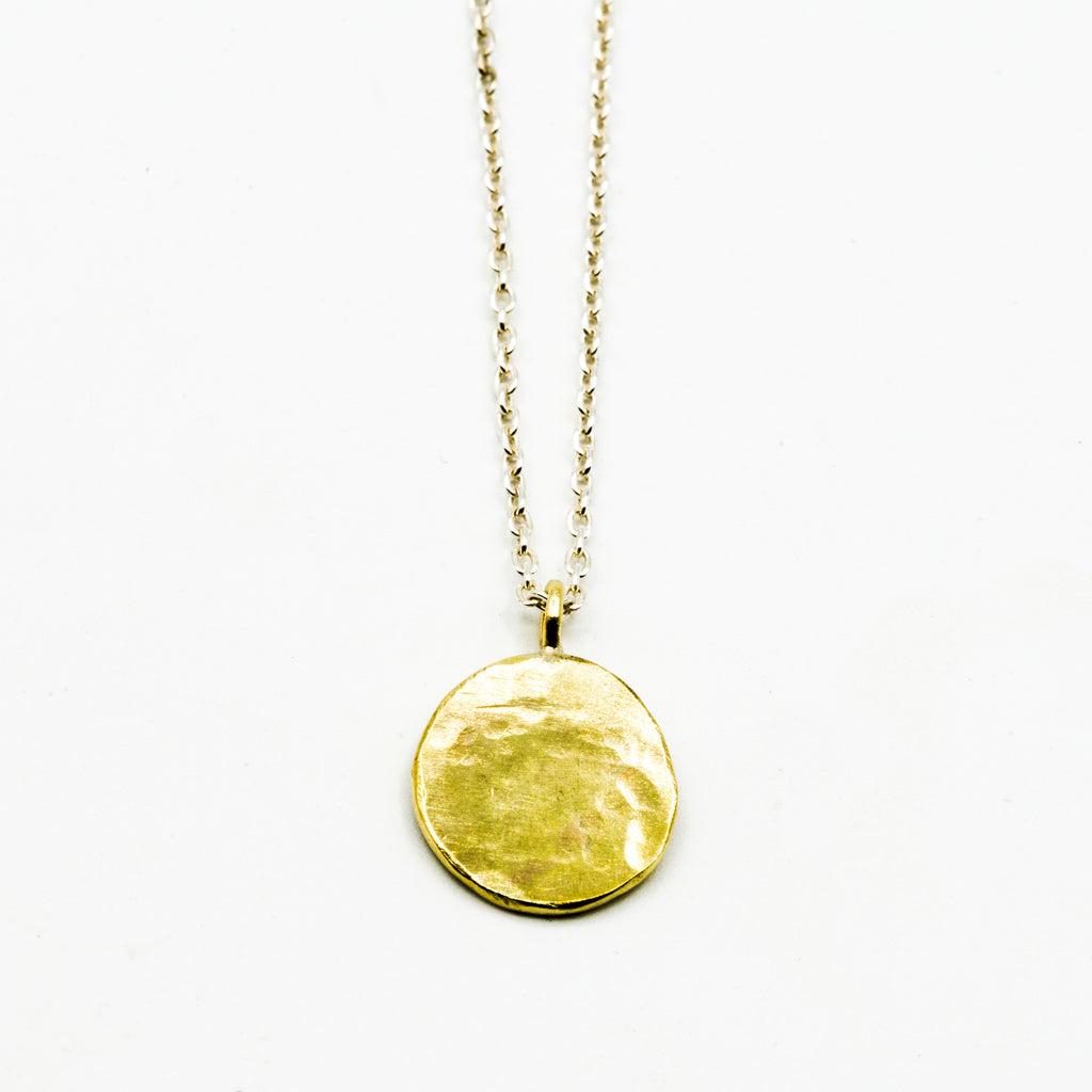 Brass circle pendant with sterling silver chain on white background
