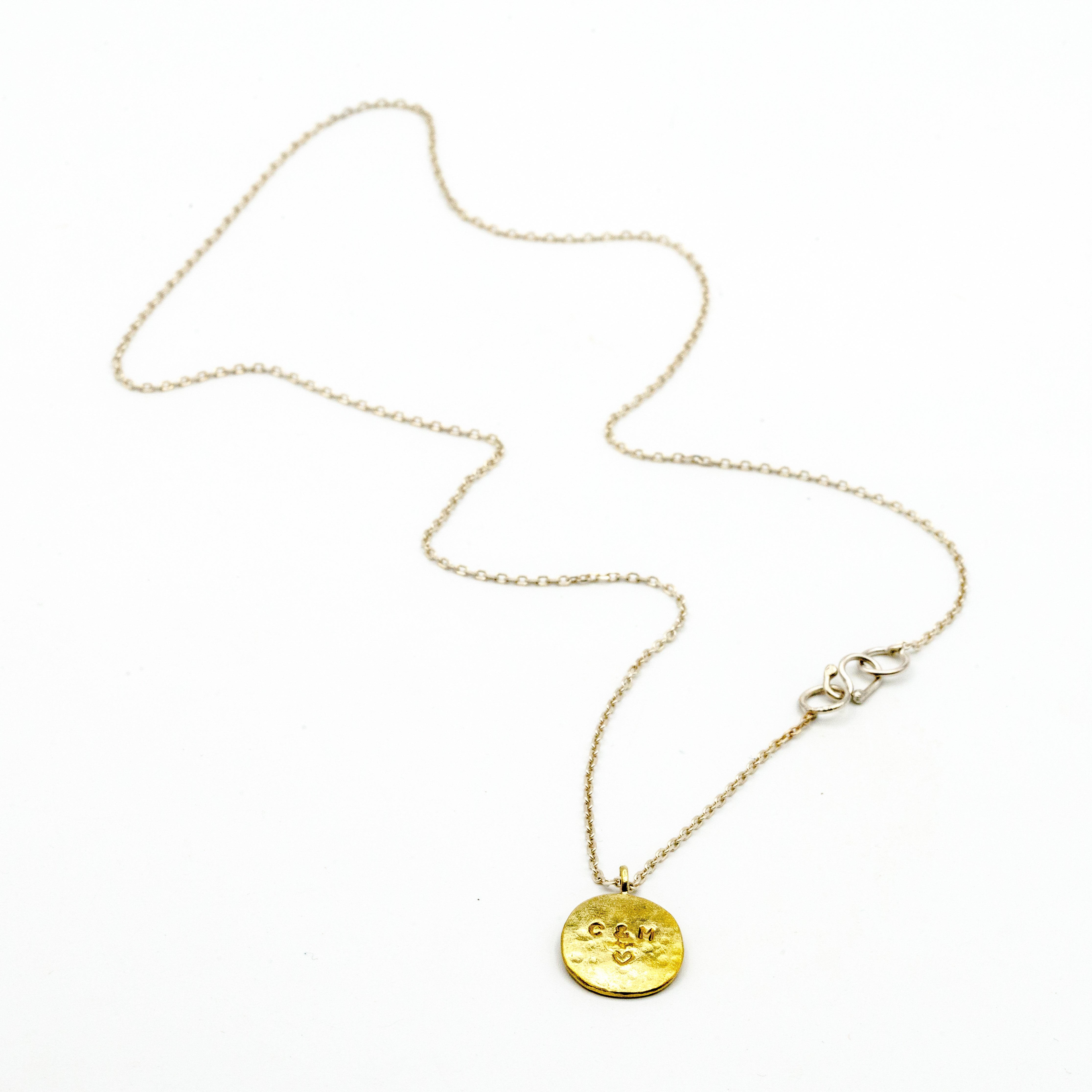 Brass circle pendant with sterling silver chain on white background