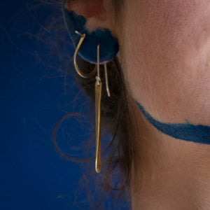 Model using long brass earrings and arch hoops