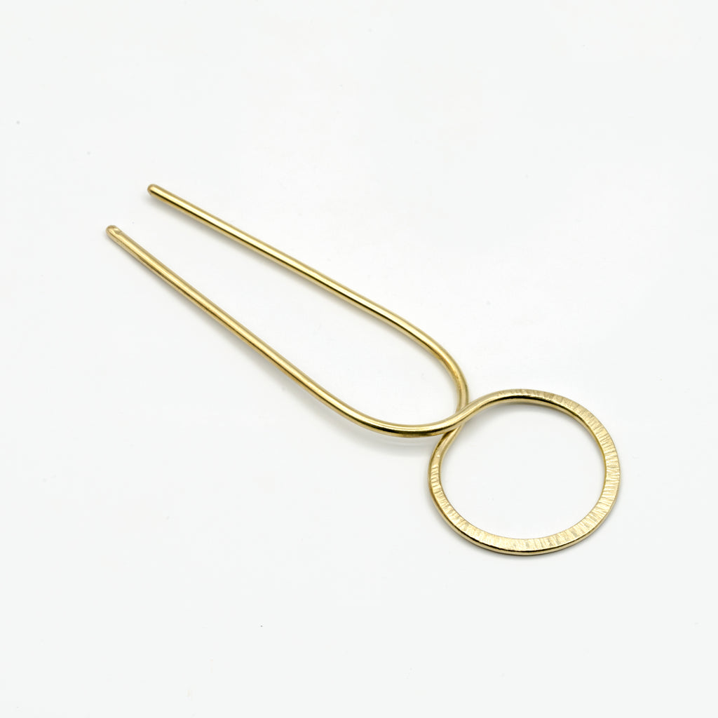 brass hair pin with striped texture on white background