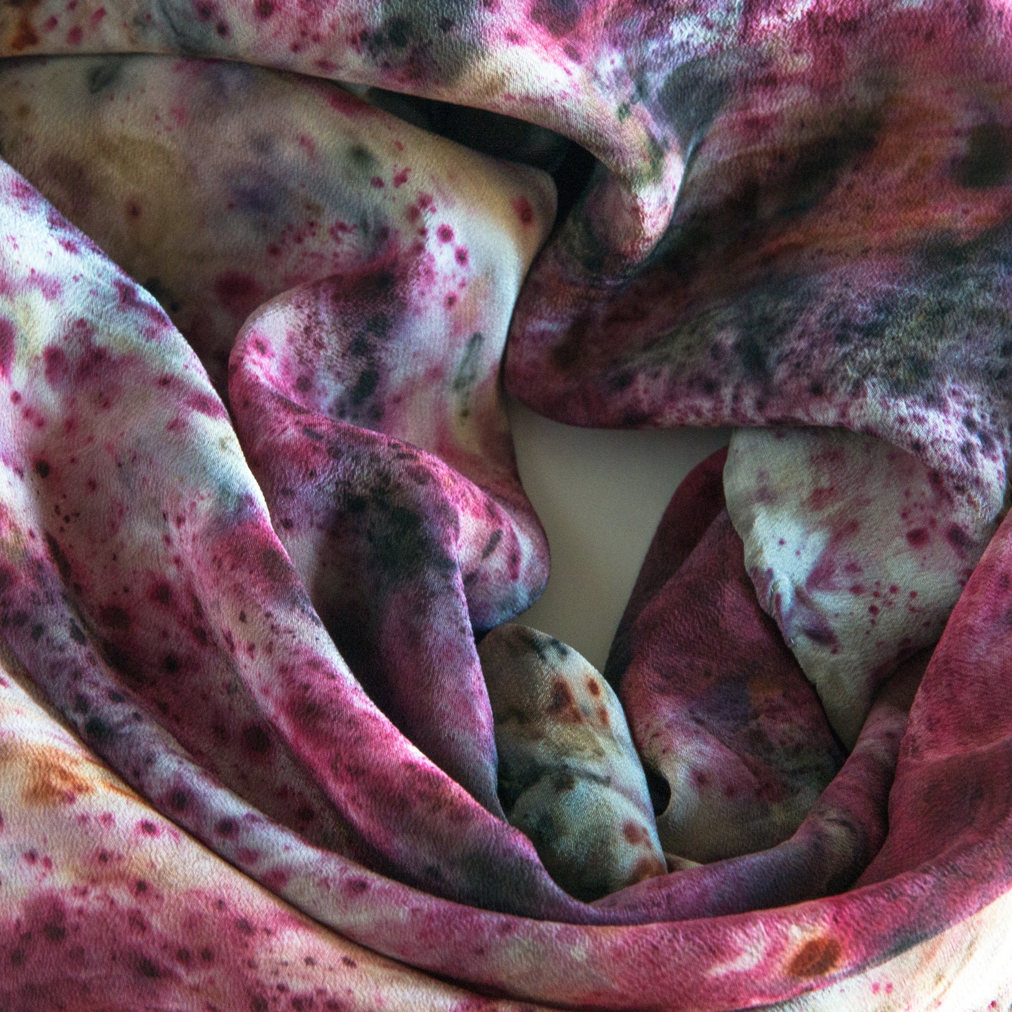 close up of rolled silk scarf. specks of many colours
