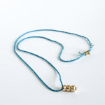 Sculpted brass pendant on this blue silk rope