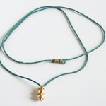 Sculpted brass pendant on this green silk rope