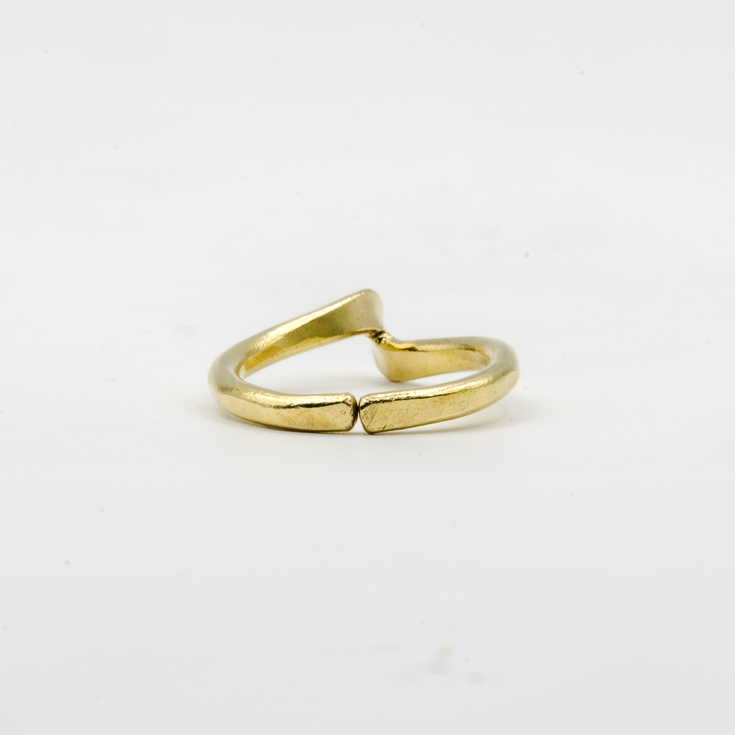 back view of hand forged curved brass ring on white background