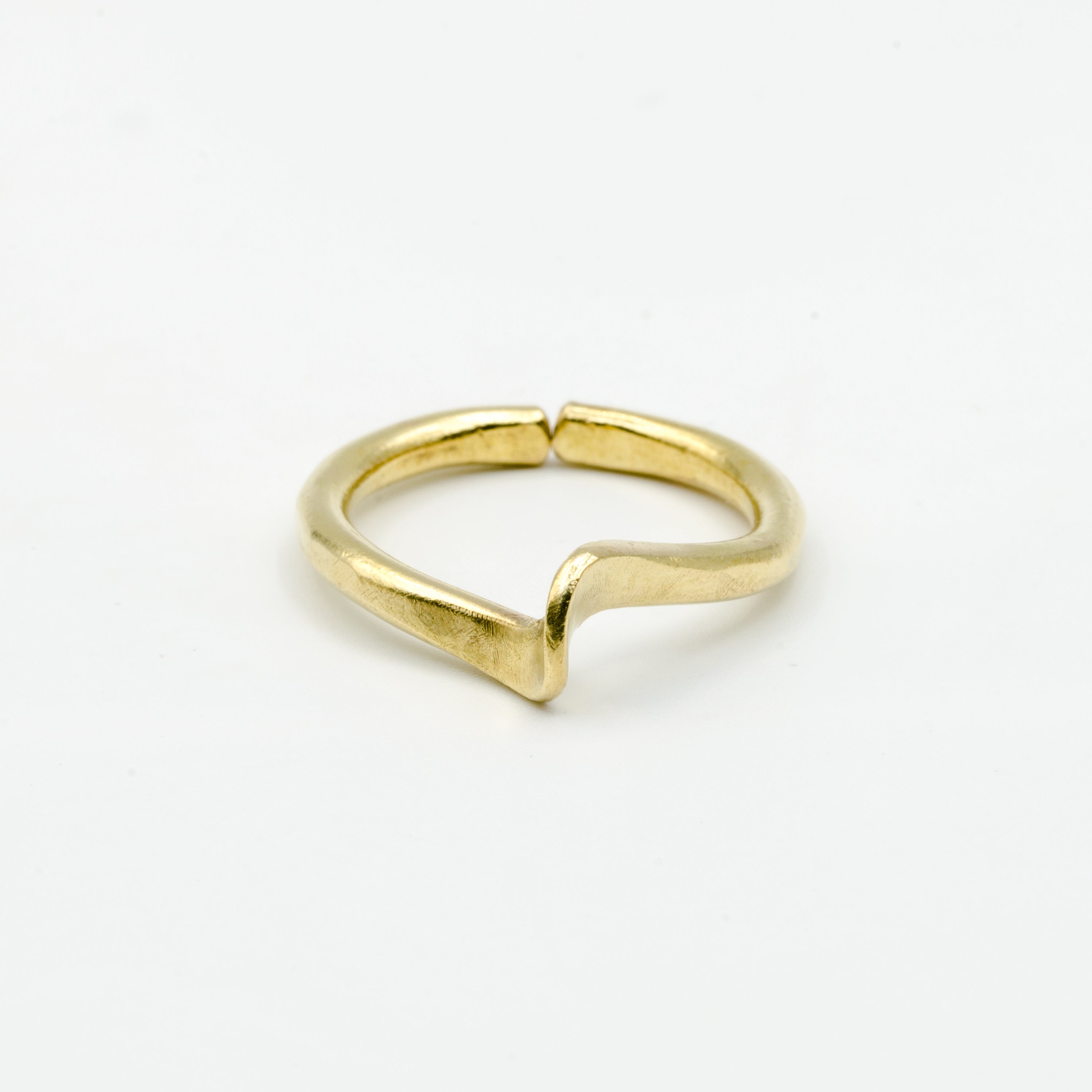 top view of hand forged curved brass ring on white background
