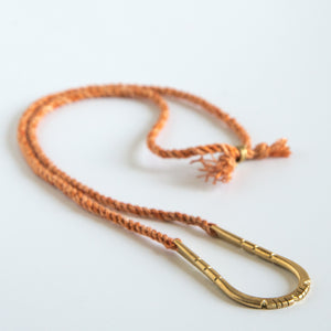U shaped hand carved pendant on orange silk rope