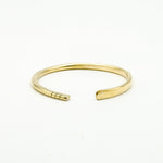 hand forged brass bangle with three cut notches on white background