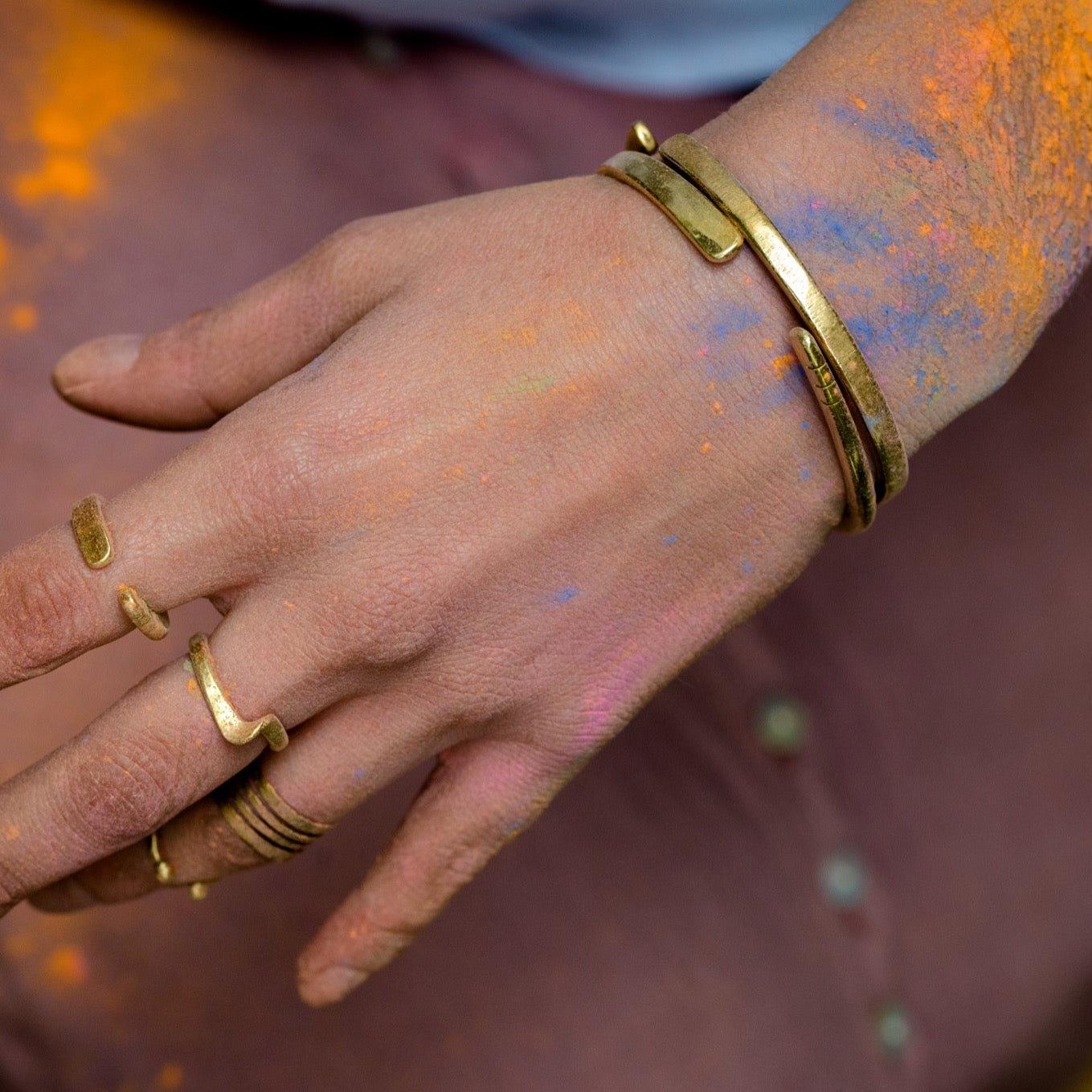 model wearing hand forged brass bangle with three cut notches and rings