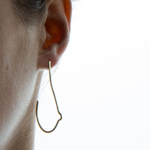 model wearing breast shaped brass wire earrings on white background